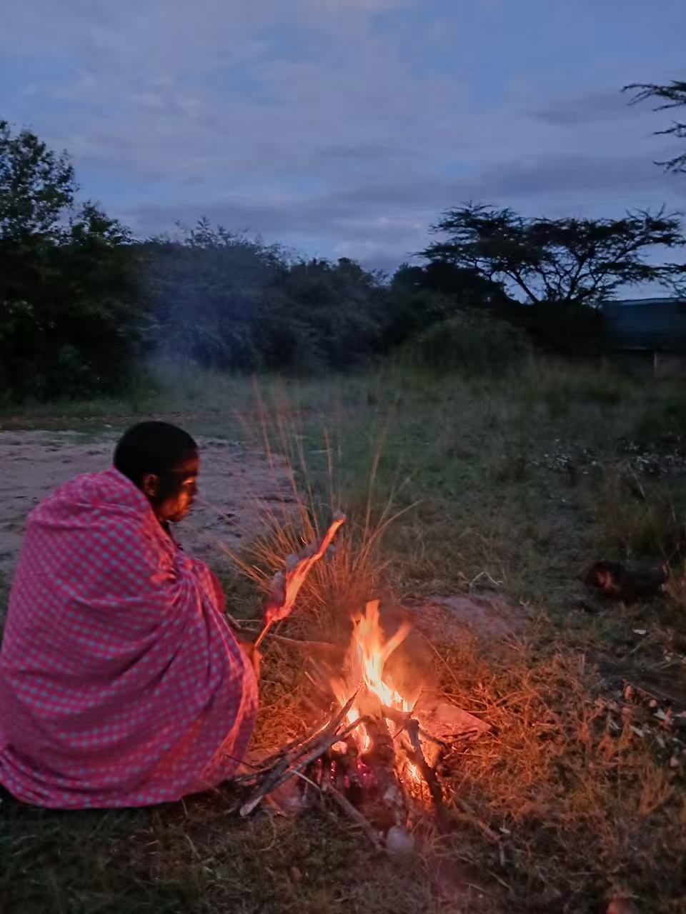 Maasai firekeeping at dusk near camp